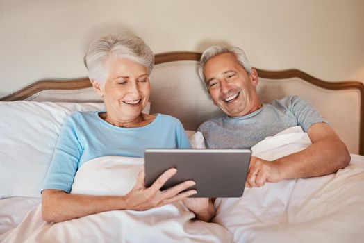 What do you think. a happy senior couple sitting together in bed and using a tablet in a nursing home.
