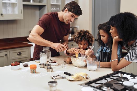 Baking is a great way to brings the family together. a young couple baking at home with their two children.