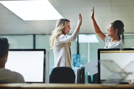 High five, teamwork and winning are important to a successful professional collaboration at work together. Happy and excited businesswoman celebrates a job promotion with a coworker at the office