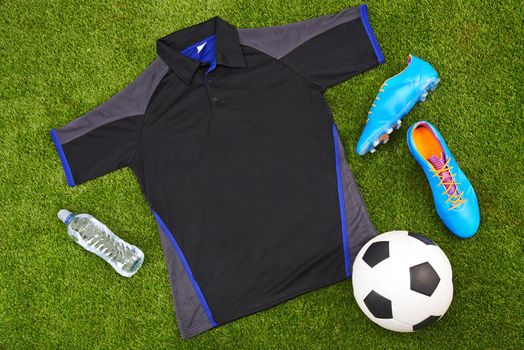 Flatlay of sportswear or trendy soccer clothes, accessories and equipment on grass background. above view of modern sporty, active or fitness wear clothing style with water bottle, ball and trainers