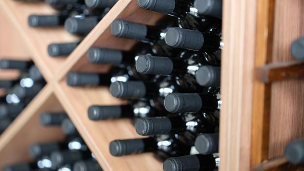 Red wine bottles stacked on wooden racks closeup