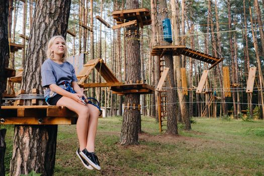 A girl passes an obstacle in a rope town. A girl in a forest rope park