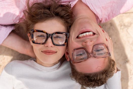 Two attractive students wearing stylish glasses lying on the floor