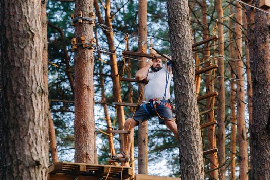 A man overcomes an obstacle in a rope town. A man in a forest rope park