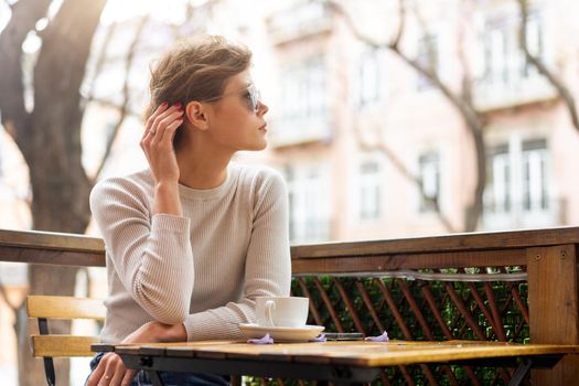 Portrait of thoughtful young woman sitting outdoor cafeteria