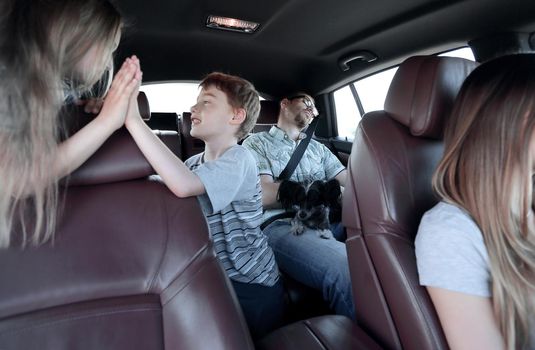 brother and sister give a high five while sitting in the car cabin