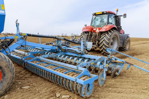 The sowing equipment is attached to the tractor and stands in the field. Agricultural sowing equipment.