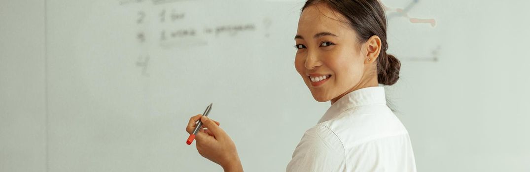 Portrait of asian business woman on background of project planning flipboard looking camera