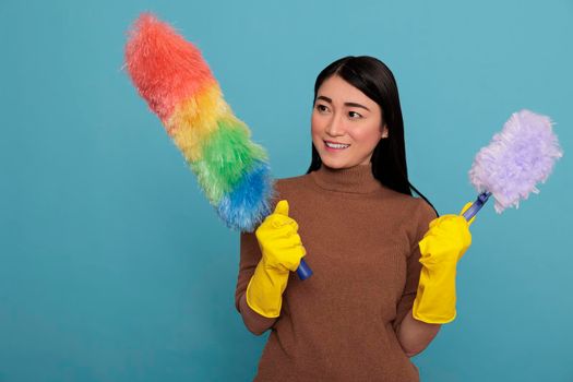 Cheerful happy and smiling asian young woman holding two duster brush