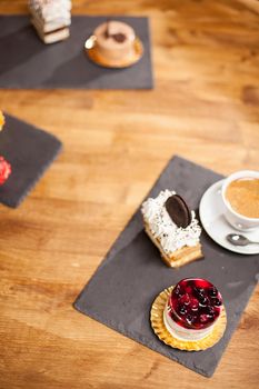 Top view photo of cake with tasty biscuit near different mini cakes on a wooden table in a coffee shop
