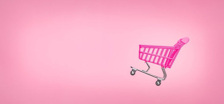 Sale cart shop banner E online. Empty trolley cart isolated pink background. Pink shopping trolley supermarket concept. Banner pink concept sales online shopping cart supermarket sales shopping symbol