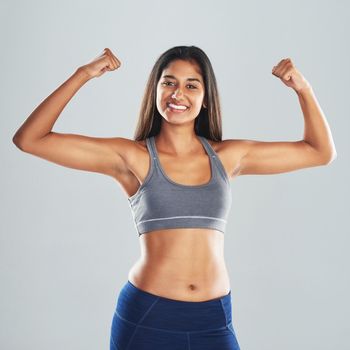 Never stop building your muscles. Cropped studio portrait of an attractive young woman flexing her biceps against a gray background.