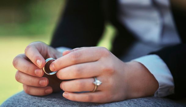 So much sadness in a single ring. Closeup shot of an unrecognizable businesswoman holding a wedding ring while sitting in a public park.