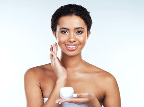 Apply the cream gently. Portrait of an attractive young woman posing while applying cream to her face against a white background.