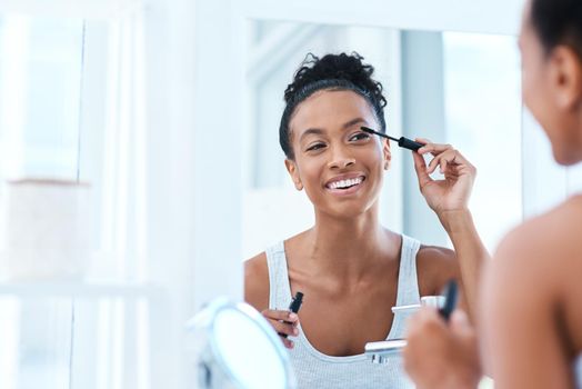 Mascara is my best friend. a beautiful young woman applying mascara in her bathroom mirror.