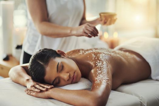 Salt scrubs impart a natural glow to the skin. a young woman getting an exfoliating massage at a spa.