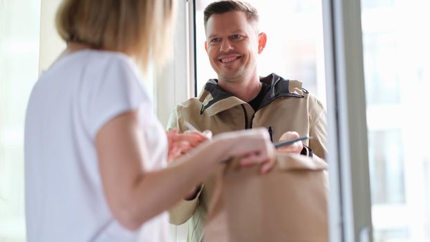 Smiling courier man delivers parcel to woman