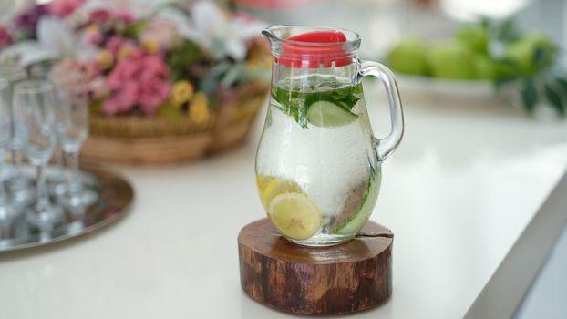 Infused detox water with cucumber, lemon and mint in jug on table