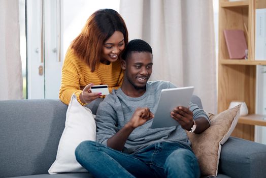 We always find better deals online than in-store. a young woman holding a credit card while browsing online with her boyfriend.