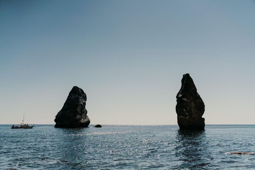 Two rocks stick out of the water in the middle of the turquoise sea. Scenic ocean views. High quality photo. Like in Iceland