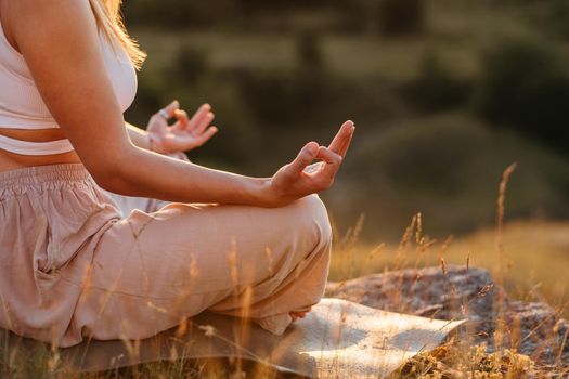 Unrecognisable Woman Connecting Fingers on Hands While Sitting on Mat, Concept of Meditation Outdoors at Sunset
