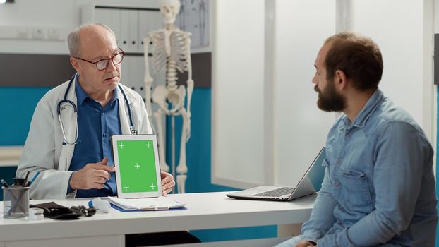 General practitioner analyzing greenscreen on device with patient