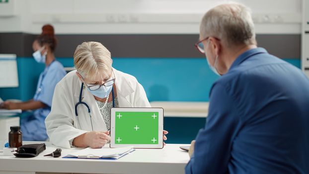 Doctor and retired person looking at greenscreen on tablet