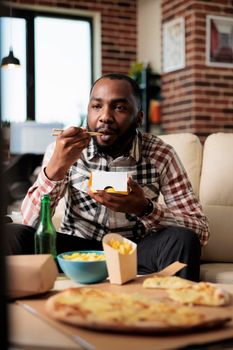 Relaxed man enjoying noodles package from takeaway delivery