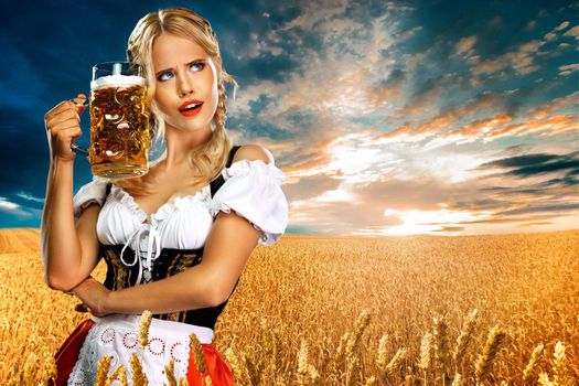 Sexy oktoberfest girl waitress, wearing a traditional Bavarian or german dirndl, serving big beer mug with drink outdoor.
