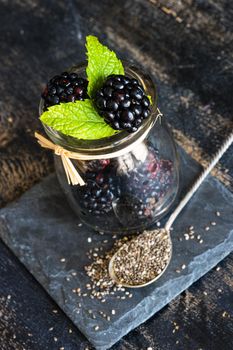 Fresh organic blackberries with mint and ice as a summer dessert concept on dark rustic table with copyspace