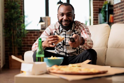 African american man using tv remote contorl to switch channel