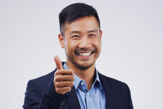 Excellent work. Studio portrait of a handsome young businessman giving a thumbs up against a grey background.