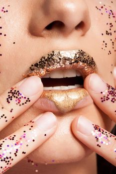 Woman with golden lips and glitter on her hands in studio