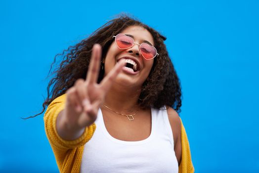 I choose peace and happiness. a young woman showing the peace sign against a blue background.