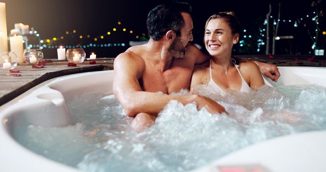 Celebrating our anniversary in style. an affectionate mature couple relaxing in a hot tub together at night.