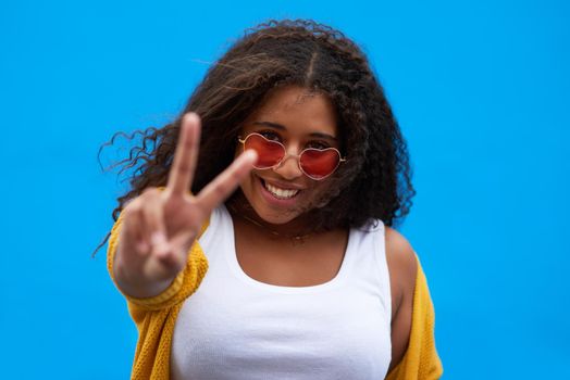 Its the peace that keeps me happy. Cropped portrait of an attractive young woman showing the peace sign against a blue background.