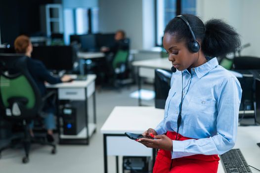 African female call center employee using smartphone.