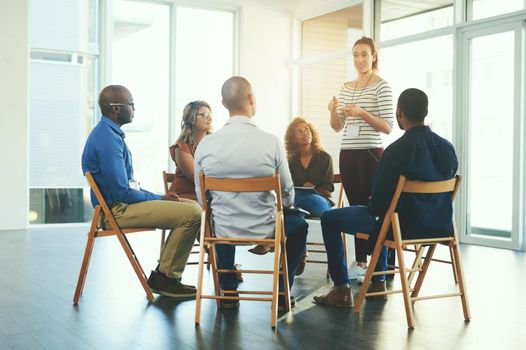 Female manager or CEO talking in a teamwork meeting about team development and success. Group of marketing team talking about a work strategy together in a coaching or training seminar at a company