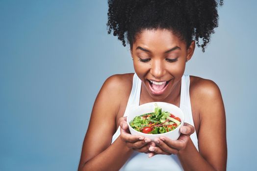 It looks amazing and taste even better. Studio shot of an attractive young woman eating salad against a grey background.