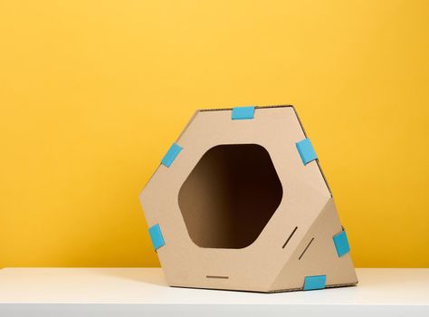 Brown cardboard modular house with a hole for cats and animals on a yellow background