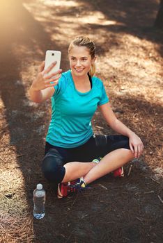 This is my mood after each workout. a sporty young woman using her cellphone while out in nature.