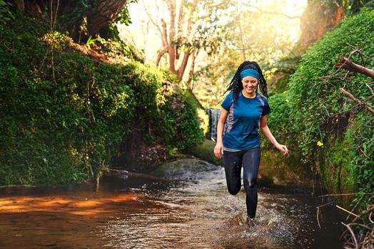 Exercise and have fun while doing it. a sporty young running through a stream of water in nature.
