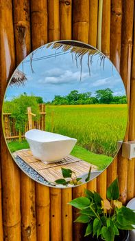 white bath tub outside on vacation at a homestay in Thailand with green rice paddy field
