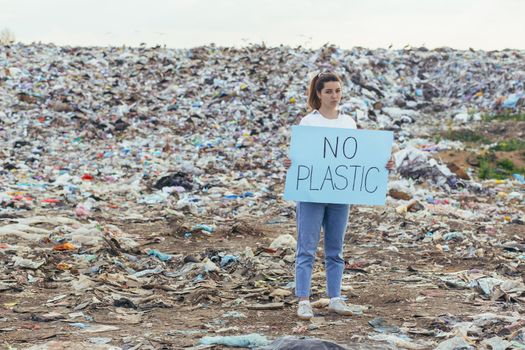Woman at landfill volunteer holding a poster save the earth
