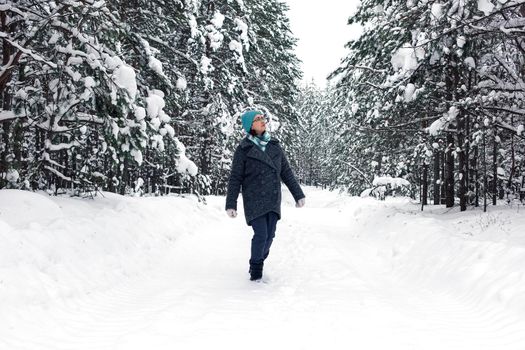 A woman is walking in the winter snowy forest.
