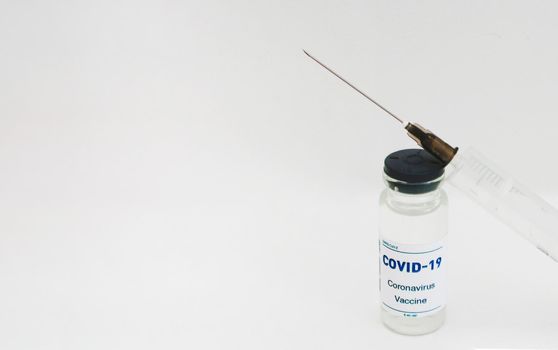 Ampoule with covid-19 vaccine and syringe on a white background.