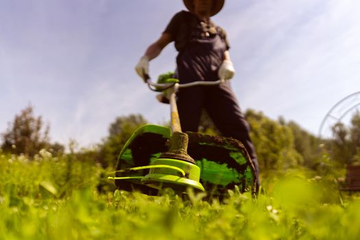 man is actively mowing a lawn with a lawn mower in his beautiful floral garden,