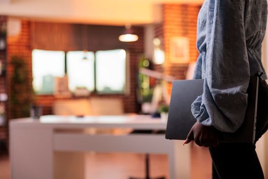 Female remote worker holding laptop in home office