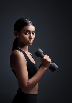 The journey to your fitness goals begins now. Studio portrait of a young sportswoman doing dumbbell exercises against a gray background.