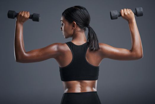 Get a grip on your goals. Studio shot of a sporty young woman lifting weights against a grey background.